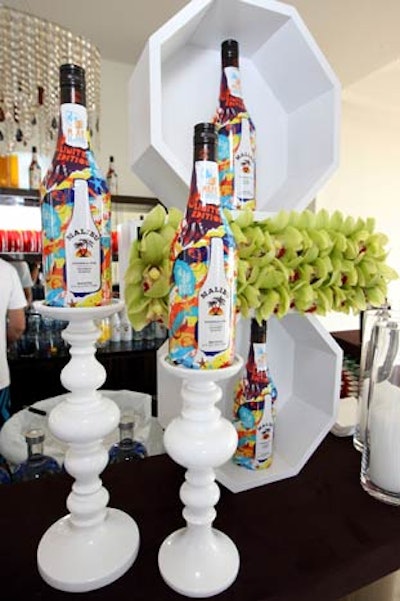 On a bar, Malibu bottles topped pedestal candlesticks.