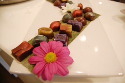 A pink flower adorned at tray of chocolate truffles atop the bar.