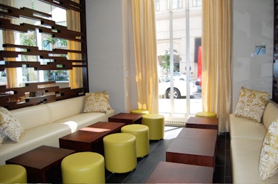 Lounge seating for 26 consists of white leather banquettes, yellow hassocks, and low wooden cocktail tables.