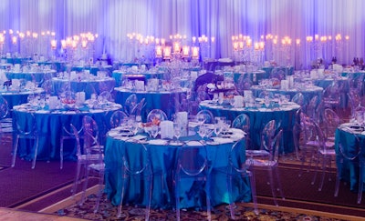 Blue linens topped tables surrounded by Victoria Ghost chairs by Philippe Starck in one of the dining sections.