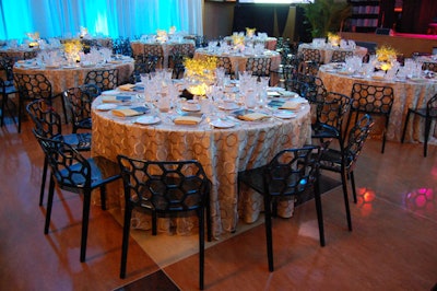 Gold linens topped tables surrounded by black honeycomb chairs from Signature Event Rentals.