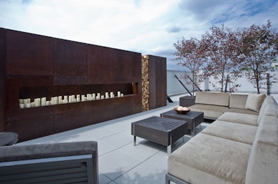 Outside a master bedroom, Joahnnah Kornak for Holly Hunt created a minimalist living area on the balcony, using dozens of candles for the fireplace wall.