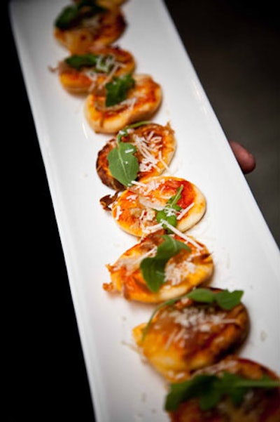 10tation Event Catering served individual pizzettes topped with fresh herbs, prosciutto, and baby arugula.