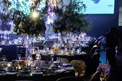 A mix of tall and short centrepieces with white roses, gerbera daisies, and hydrangeas topped tables draped in gold and brown linens.