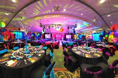 Colorful lighting, suspended spandex decor, and illuminated centerpieces transformed the ballroom into a retro party atmosphere.