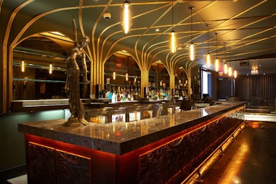 A white diamond granite counter tops the main bar, which is fronted with intricate metal panels and has griffin details on the brass foot rails.