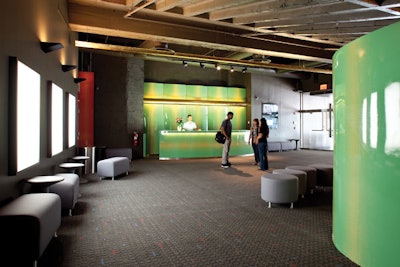 The focal points of the theater's lobby are a bar and a curvilinear wall made from luminous colored metal overlaid with stenciled designs.