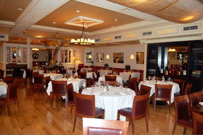 Designers used antiqued woodwork with gold accents for the walls and a wide-plank hardwood floor in the main dining room.