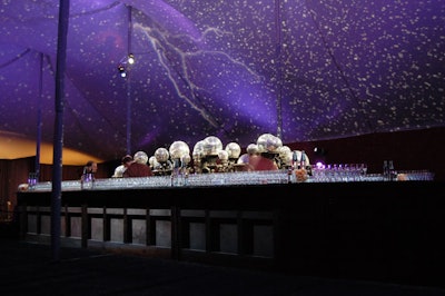 Designed to emulate a starry night sky, large disco balls set atop urns reflected hundreds of spots of light onto the tent ceiling. The look was reinforced by projections of lightning bolts.