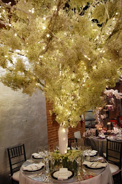 Renny and Reed created a towering tree centerpiece made of baby's breath and white lights. On the mirrored tabletop, the designers used napkins trimmed with a Greek key pattern, flowers in shades of white and green, and fancy black and gold plates.