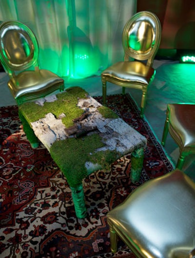 In one seating area, rough-hewn tables made of stripped birch trees, moss, and ferns contrasted with gold-colored chairs.