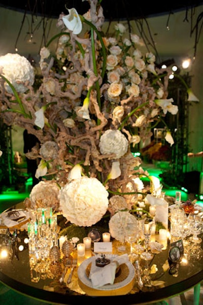 An enormous installation of branches and flowers topped the table for the garden party tableau, contrasting metallic gold accents, shiny glassware, and framed photographs of founder Louis Vuitton.