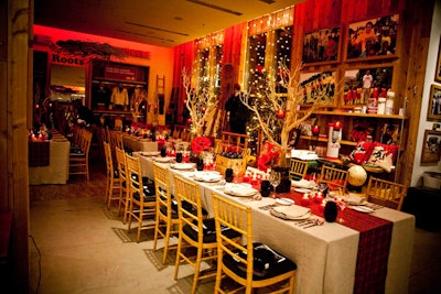 Red tartan table runners and centrepieces featuring red amaryllis and tall branches topped tables for the dinner held on the second floor of the Roots store.