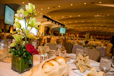Centerpieces by Encore Décor featured dark red roses, greenery, and an orchid spray.