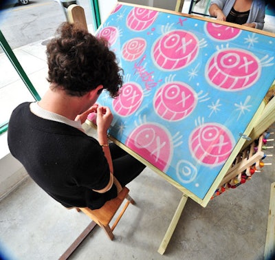 Fendi commissioned graffiti artist Andre to spray paint three large needlepoint panels that students from Miami's Design and Architecture Senior High are stitching as part of a competition for a personalized Fendi handbag.