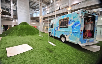 Cynthia Rowley's exhibit space, located in the atrium of the 4141 building, consisted of her signature shop on wheels, used for trunk shows around the country, and an artificial grass hill. Each designer participating in Limited Editions created a special product to sell during the show; Rowley sold outdoor mats screened with the word 'Relax. '
