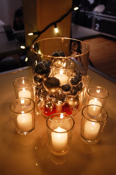 Glass vases filled with candles and silver holiday ornaments topped cocktail tables throughout the space.