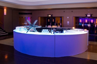 Servers offered cocktails to guests at a round bar topped with a silver star ornament.