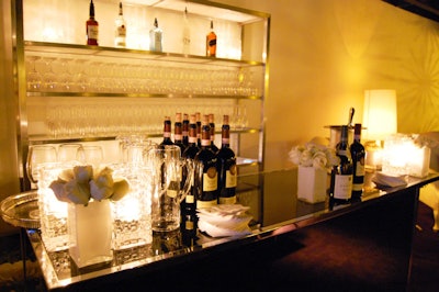 Vases filled with cream roses topped a black bar in the event space.