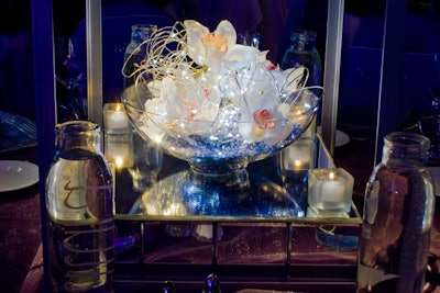 Bowls of amaryllis blossoms, blue crystals, and tiny white lights sat atop mirrored boxes at the base of the centerpieces.