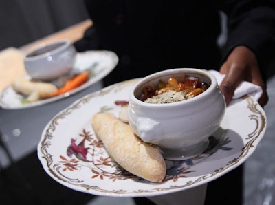 For the main course, Restaurant Associates served a duck cassoulet with lardons, pork sausage, white beans, and roasted root veggies, served alongside a baguette on a plate decorated with images of birds.