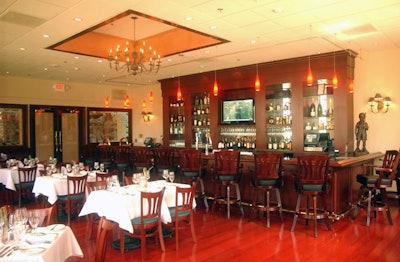 The dining room is decorated with cherry floors and chairs, and tables topped with simple white linens.