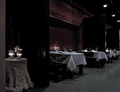 White linen tablecloths and candlelight create an intimate environment at the front of the space, where nine tables seat four guests apiece.