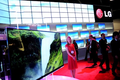 LG's dramatic booth beckoned guests with bright wraparound screens made from three panels at the exhibit's entrance. Sleek white cabinetry marked the displays, and white panels overhead glowed with LED patterns. Sparks Los Angeles created the exhibit.