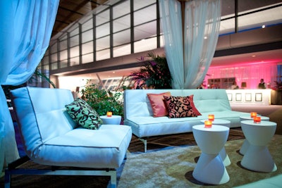 A raised gazebo-like area with futon couches, gauzy curtains, and white cocktail tables was set up in the convention center's pre-function space.