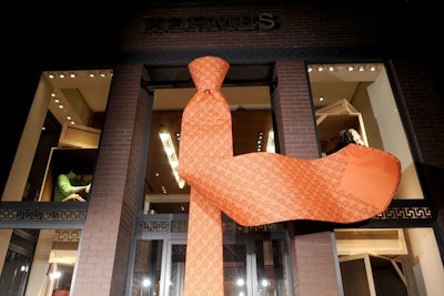 Greeters at the new store, which was covered in a giant orange tie, were clad in black topcoats with Hermès orange scarves.