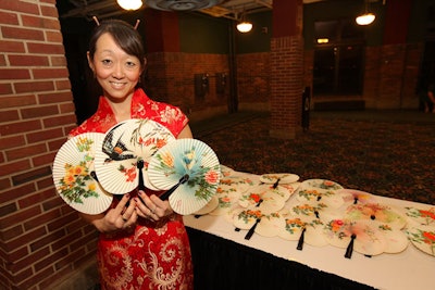 A staffer dressed in traditional Chinese attire doled out keepsake fans as guests left the ball.