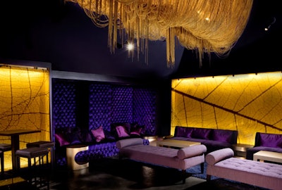At Bar210, enlarged photos of gold leaves create a backdrop for purple tufted lounge furniture and offset a hand-hung gold beaded chandelier.