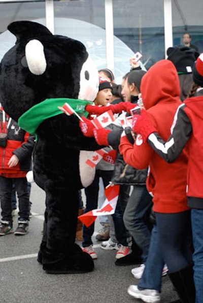 People dressed as Olympic mascots Miga, Quatchi, and Sumi meet with visitors in and around the pavilion.