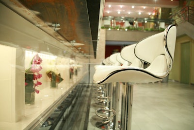 An illuminated recess below the dining counter is filled with red and white orchids.