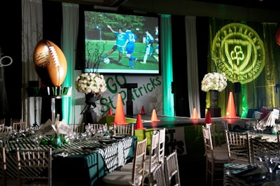 In addition to the green-and-white tablecloths and orange cones lining the stage, on-theme touches included gobos of the school seal and projected images of student athletes.