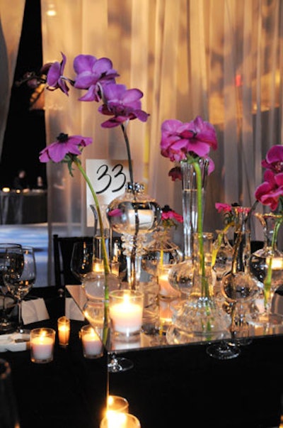 Winston Flowers created table centerpieces comprised of multilevel glass vases and votives accented by hot pink orchids.