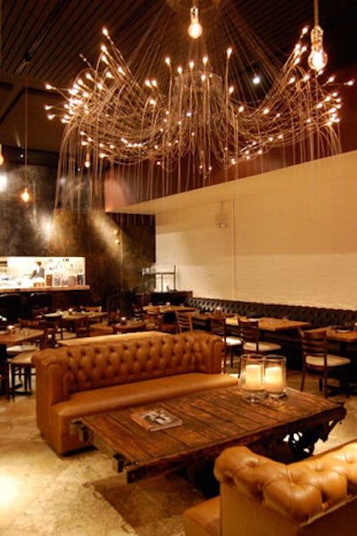 Salvaged wood fixtures, leather sofas, and an oversize chandelier deck the interior of Gilt Bar.