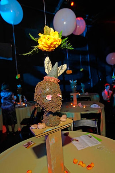 On low tables, centerpieces included mossy heads decked with flower eyes and winged birthday hats.