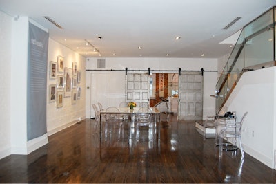 The second-floor gallery has stained oak floors, exposed brick walls, and salvaged garage doors that slide to reveal the kitchen.