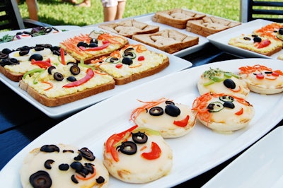 A table with kid-friendly snack options served funny-face pizzas.