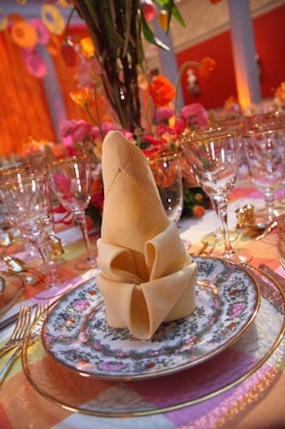 Sferra Hemstitch napkins in pumpkin, raspberry, and white were folded into 'corn on the cob' patterns atop Rose Medallion plates, adding to the atrium's spring-themed tabletops.