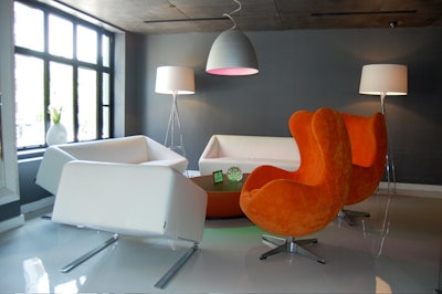 White leather sofas and a pair of sculpted chairs upholstered in orange velvet fill a corner overlooking K Street.