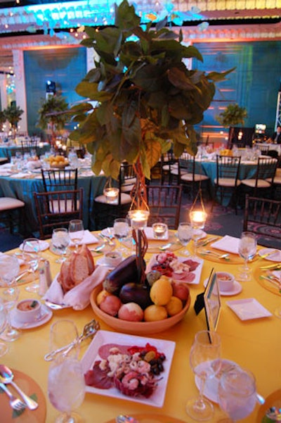 Topiary trees adorned with hanging tea lights and ceramic bowls filled with eggplants, onions, and lemons served as centrepieces.