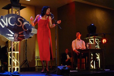 Performer Adrienne Griffiths circulated as a raffle-ticket-selling cigarette girl for the evening's cocktail portion. Upon being called on stage as the winning ticketholder, she unveiled her floor-length red gown and performed.