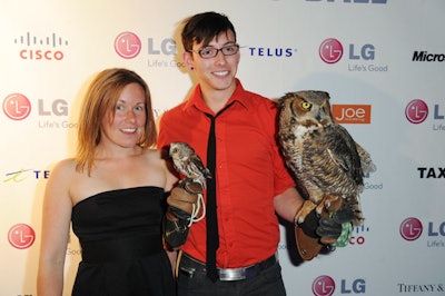Handlers posed with owls in front of a step-and-repeat bearing the names of event sponsors like LG Electronics Canada and Telus.