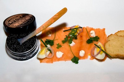 Wolfgang Puck Catering's first course, referred to on the menu as the 'Opening Act,' paired domestic caviar with smoked salmon, egg, and toasted brioche. The main course was a Wagyu beef burger stuffed with truffled short rib.