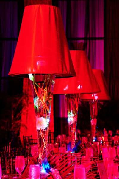 Art Flowers Corporation created centerpieces using tall clear vases filled with floating white hydrangeas and topped with large red lamp shades.