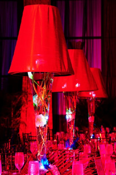 Art Flowers Corporation created centerpieces using tall clear vases filled with floating white hydrangeas and topped with large red lamp shades.