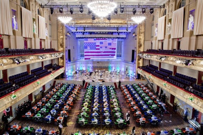 Symphony Hall's decor for the evening featured the Pops' 125th season color scheme—orange, blue, and lime green—on linens, lighting, and boxed dinners. The stage's backdrop included a screen with American flag images from High Output.