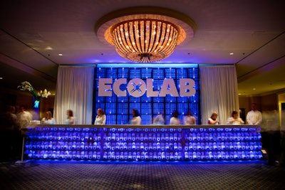 A branded registration desk incorporated Ecolab products. The base was made out of soap dispensers, and the back wall comprised glass racks from restaurant dishwashers.